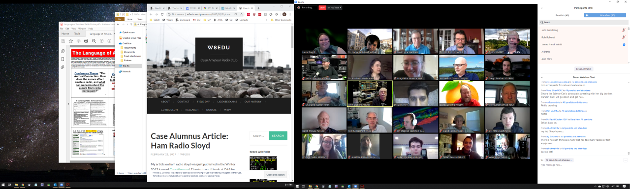 A computer screen shows several windows open. In the center is a Zoom chat meeting with a grid of participants' images