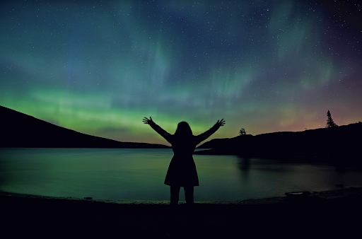 A woman joyfully motions toward the sky