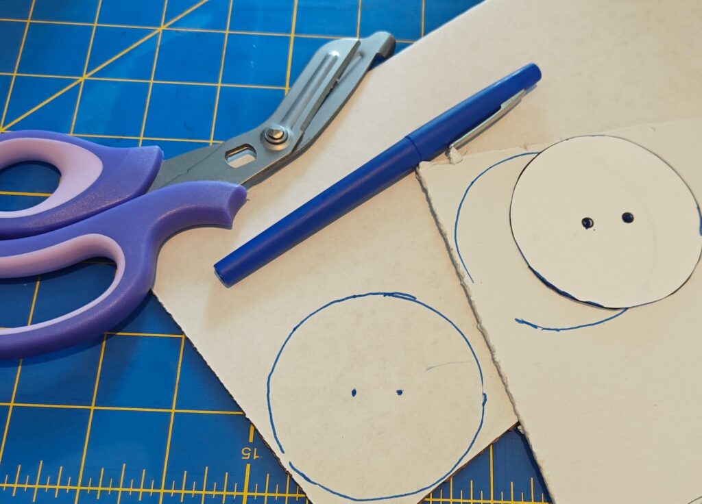 Photo shows a pen, bandage scissors, template, cardboard, and quickboard, with the template traced onto the latter two.