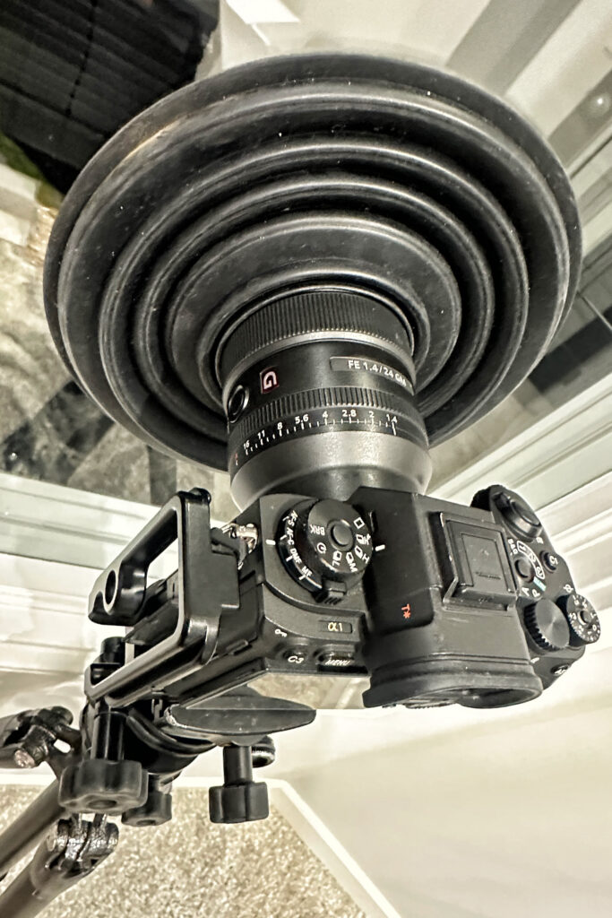 A camera is fitted with a wide, funnel-shaped hood over the lens.