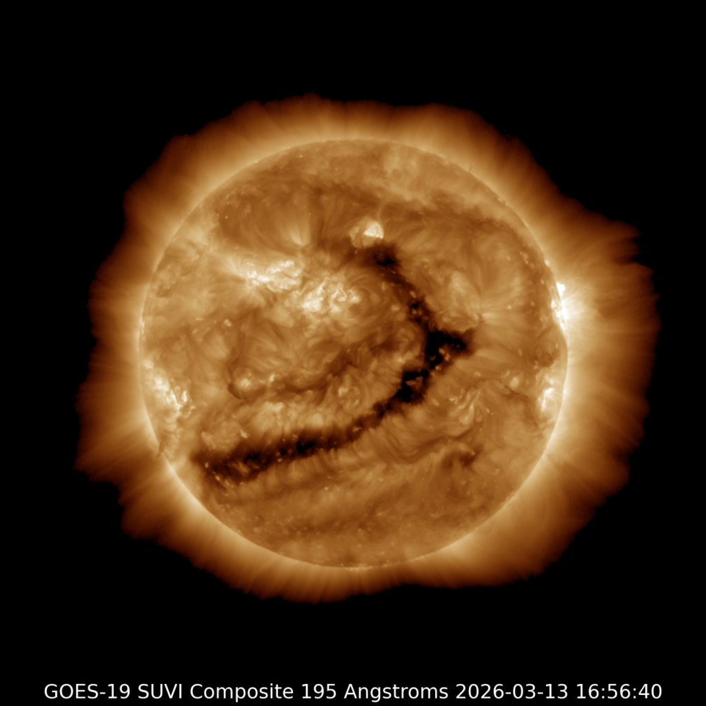 A yellow image of the Sun with a hook-shaped coronal hole stretched across the center surface, hook upward like it's beckoning.
