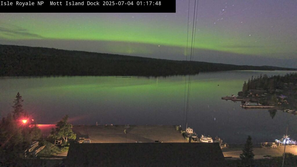 Calm, soft green aurora floats over a body of water.